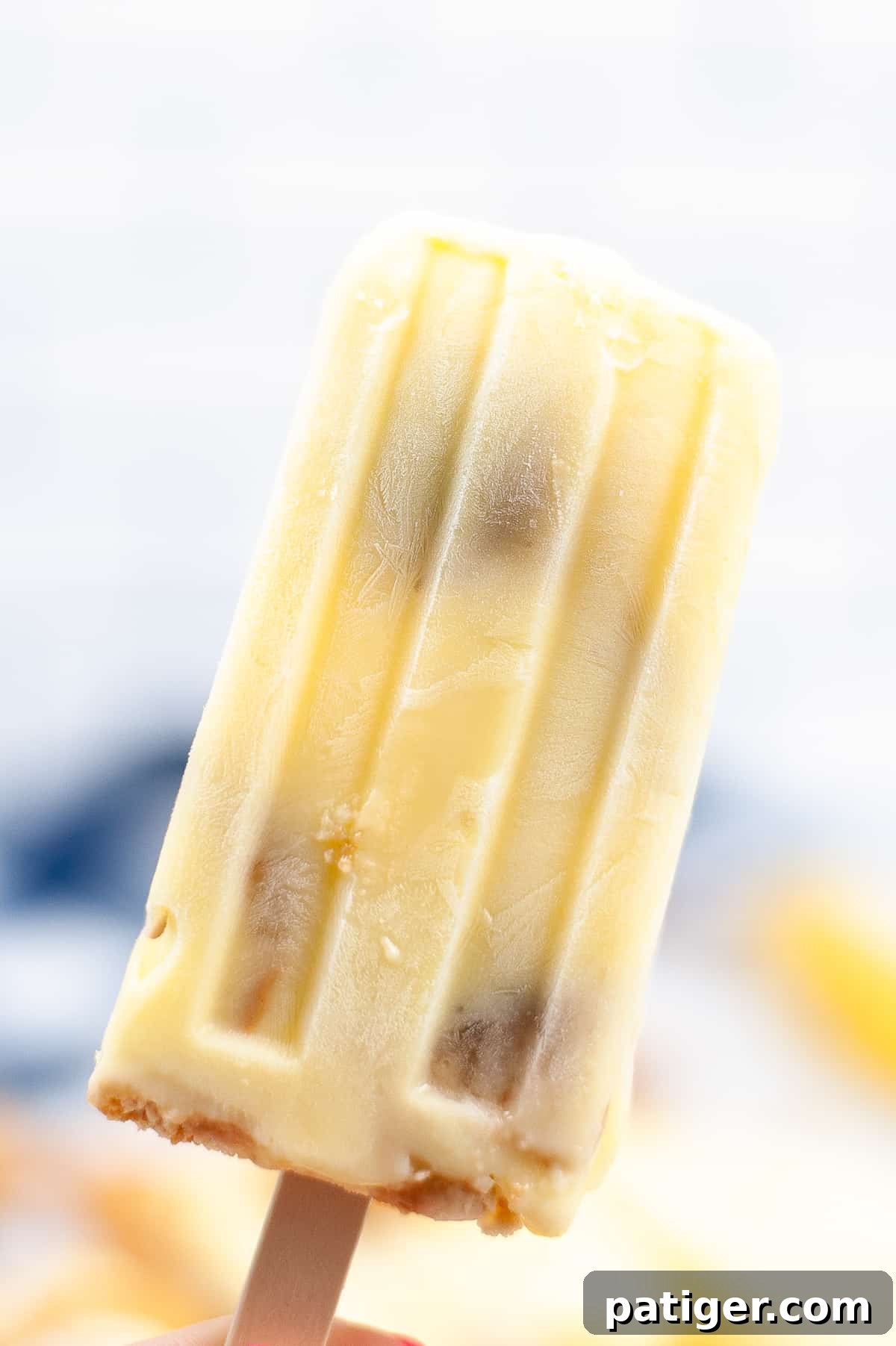 Velvet Banana Pudding Pops 3 Close-up of a single banana pudding popsicle, showing embedded banana chunks and Nilla wafer pieces