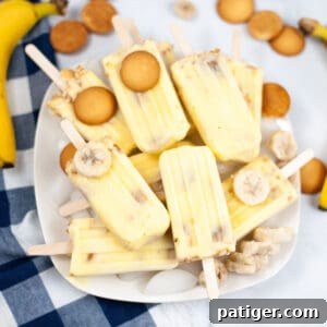 Banana popsicles piled on a platter with nilla wafers and frozen banana slices