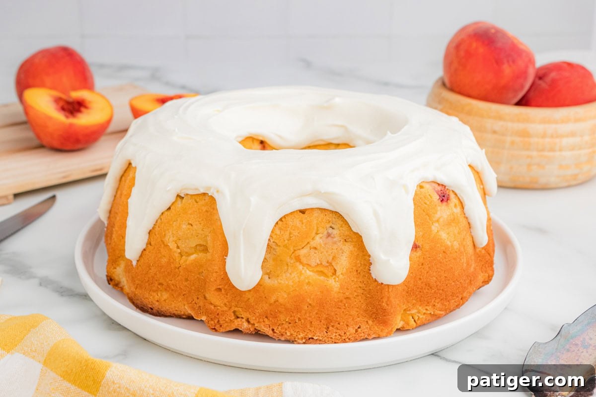 Whole peach bundt cake with cream cheese icing on a plate.