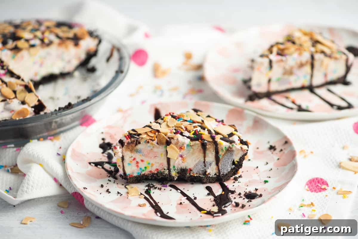 Icebox Indulgence 11 A slice o ice cream pie with chocolate crust and rainbow sprinkles. Pie is topped with drizzle of chocolate syrup and sliced almonds. Another slice and the remainder of the pie can be seen in the background.