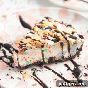 Slice of ice cream pie drizzled with chocolate sauce and topped with sprinkles and sliced almonds