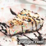 Slice of ice cream pie drizzled with chocolate sauce and topped with sprinkles and sliced almonds
