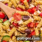 A small image of the finished Greek pasta salad, with rotini, cherry tomatoes, cucumber, olives, feta, red onion, and bell pepper.
