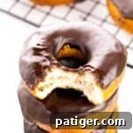Stack of chocolate glazed biscuit doughnuts with a bite taken out of the top one