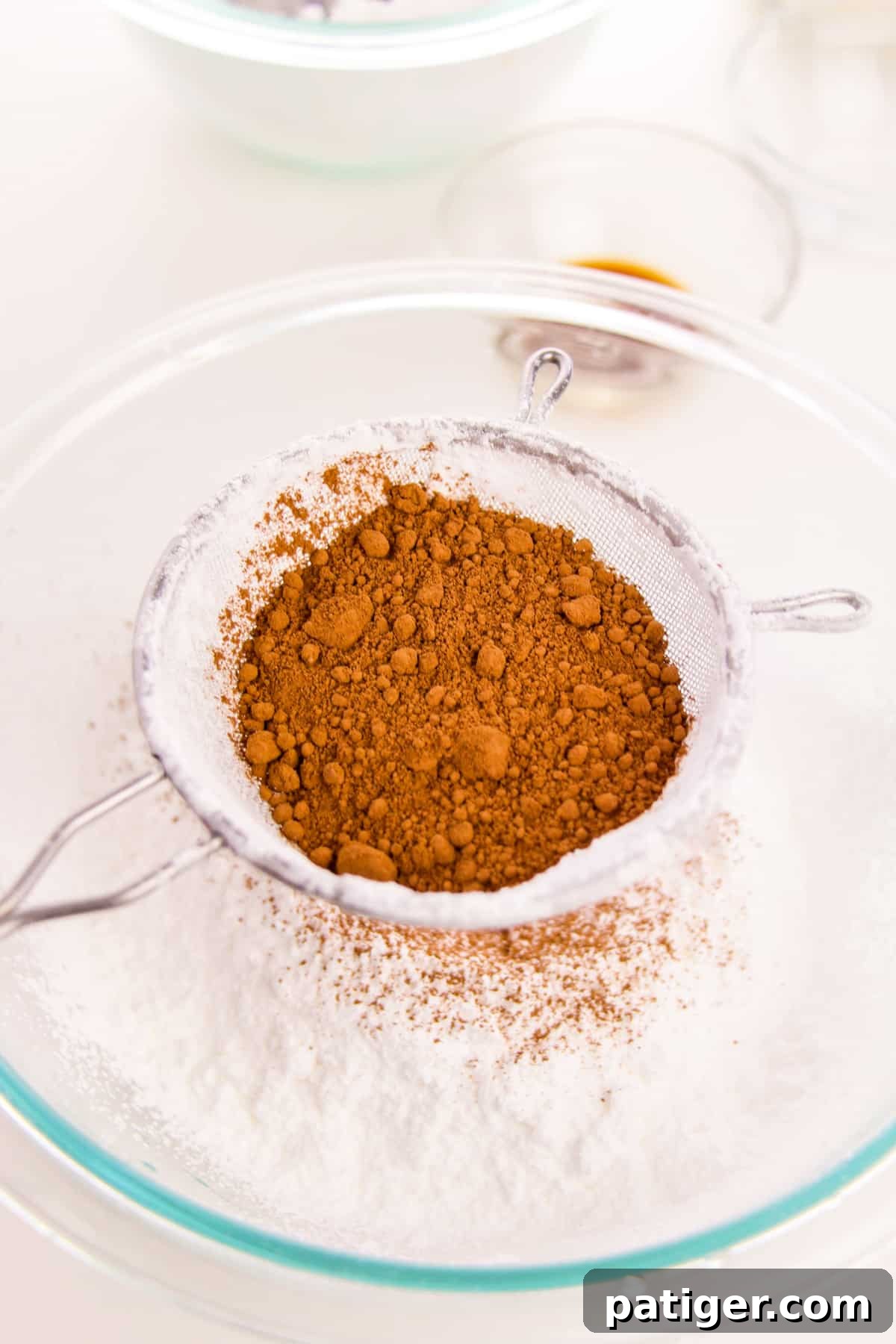 Choco-Biscuit Bliss Bites 6 Cocoa powder being sifted into glass bowl of powdered sugar