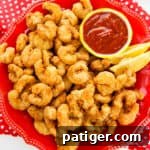 Golden Shrimp Poppers 10 Popcorn shrimp on a red plate with lemon wedges and cocktail sauce, perfect for sharing on social media.