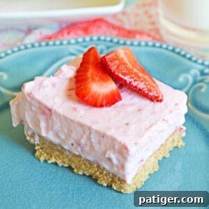 No-Bake Strawberry Cheesecake Bar with a thick graham cracker crust on blue plate topped with fresh strawberries