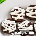 chocolate mummy cookies with strips of whit frosting and candy eyes