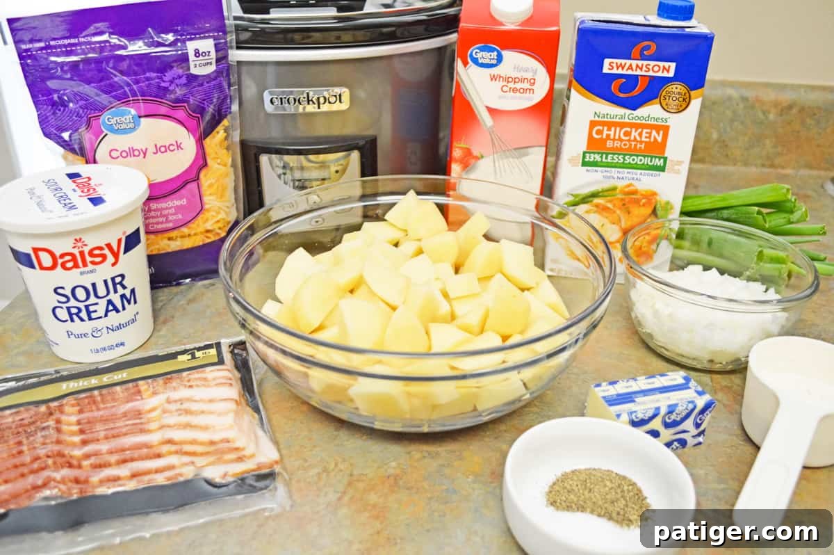 All the essential ingredients for the slow cooker baked potato soup laid out on a countertop: shredded cheese, a container of sour cream, cooked bacon, diced potatoes, heavy cream, chicken broth, chopped onion, fresh green onions, salt, pepper, butter, and all-purpose flour.