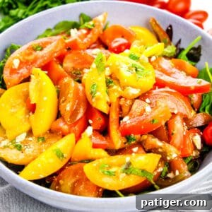 Heirloom Tomato Salad with crumbled feta on bed of lettuce in serving bowl.