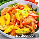 Heirloom Tomato Salad with crumbled feta on bed of lettuce in serving bowl.