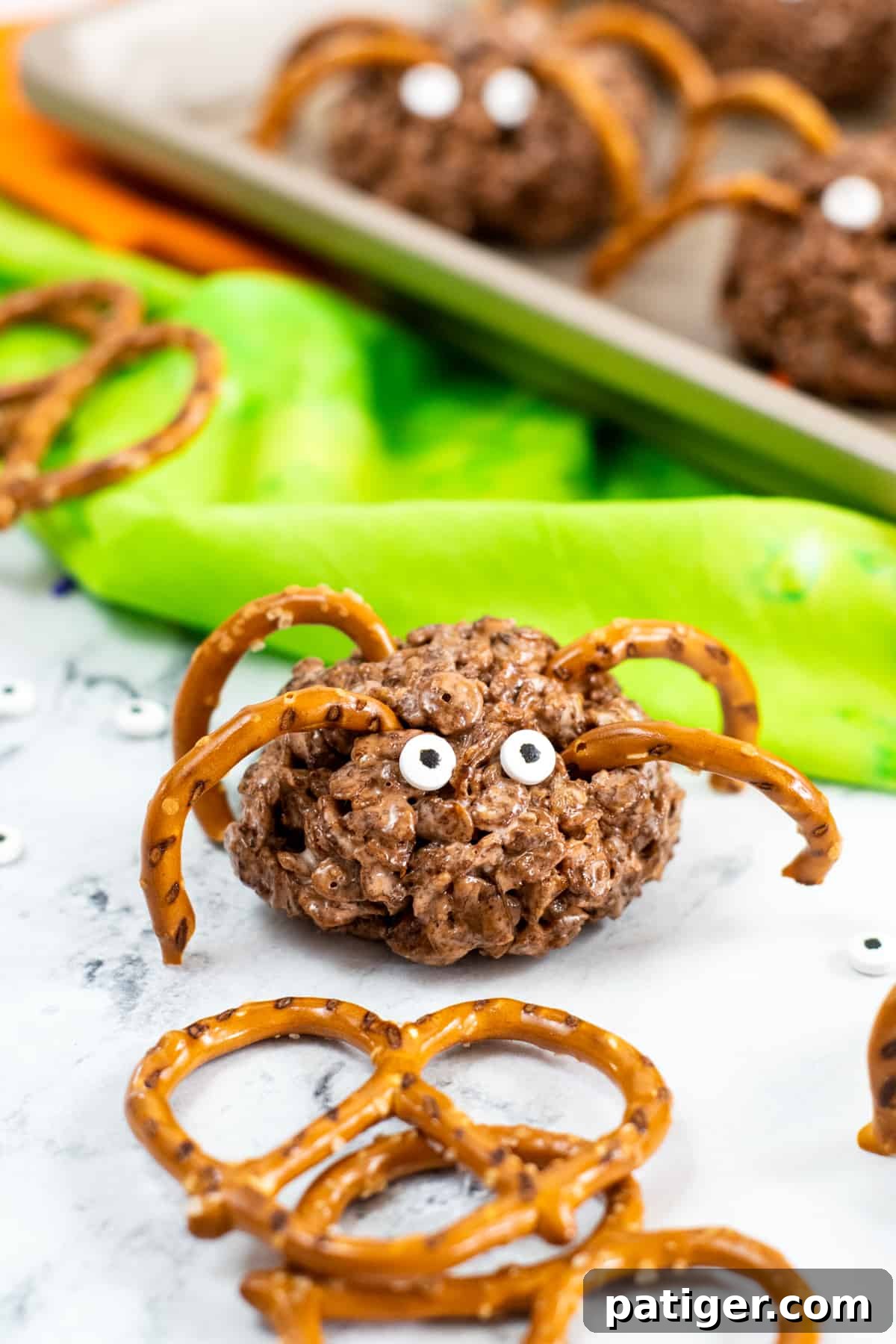 A group of brown rice krispies treat spiders with fewer pretzel pieces as legs and candy eyes arranged on a platter, showcasing a simplified design.