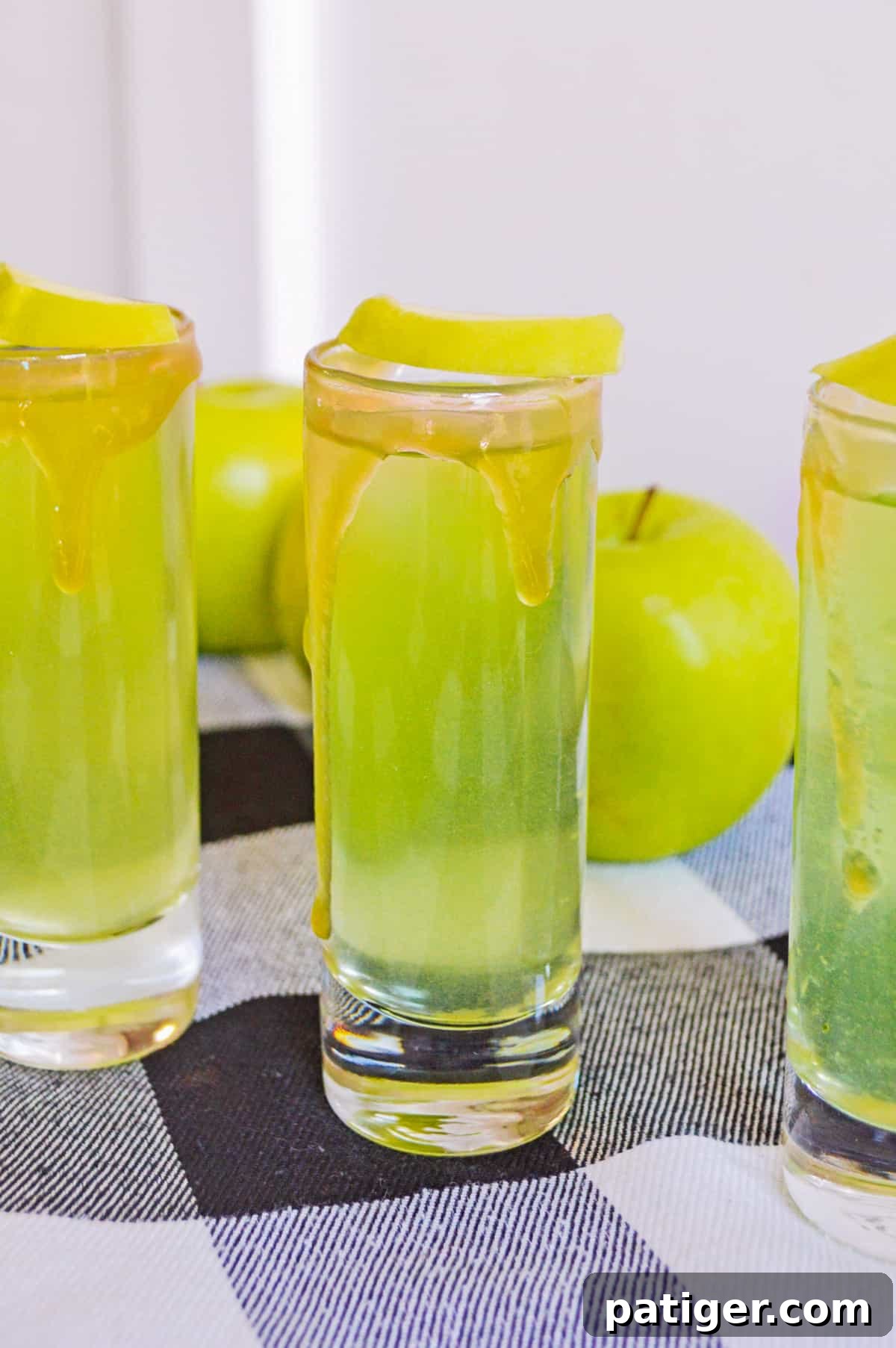 Spiced Caramel Apple Shooters 2 Caramel apple shots with caramel vodka, apple cider, and sour apple mixer, ready to be enjoyed.