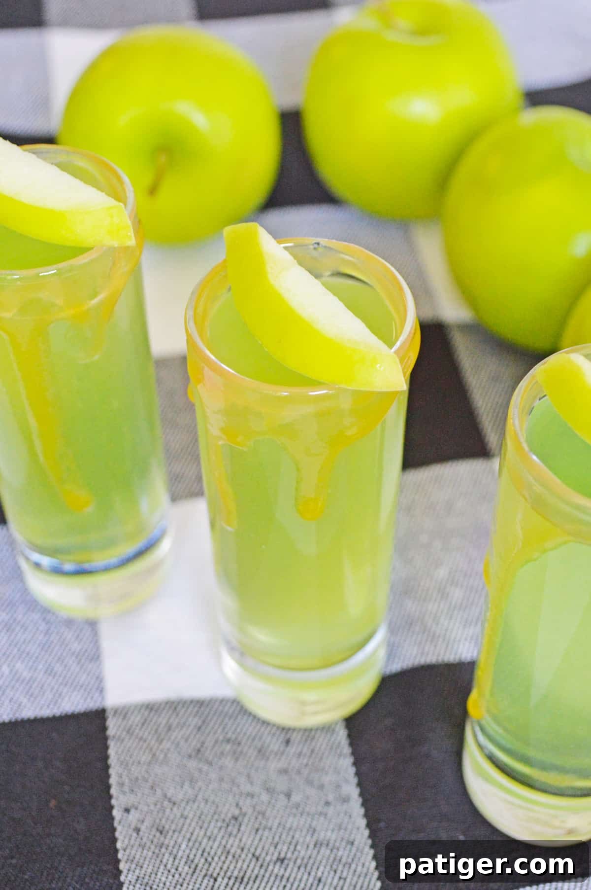 Spiced Caramel Apple Shooters 4 Caramel Apple Vodka Shots garnished with fresh apple slices and caramel drizzles, ready for a fall celebration.