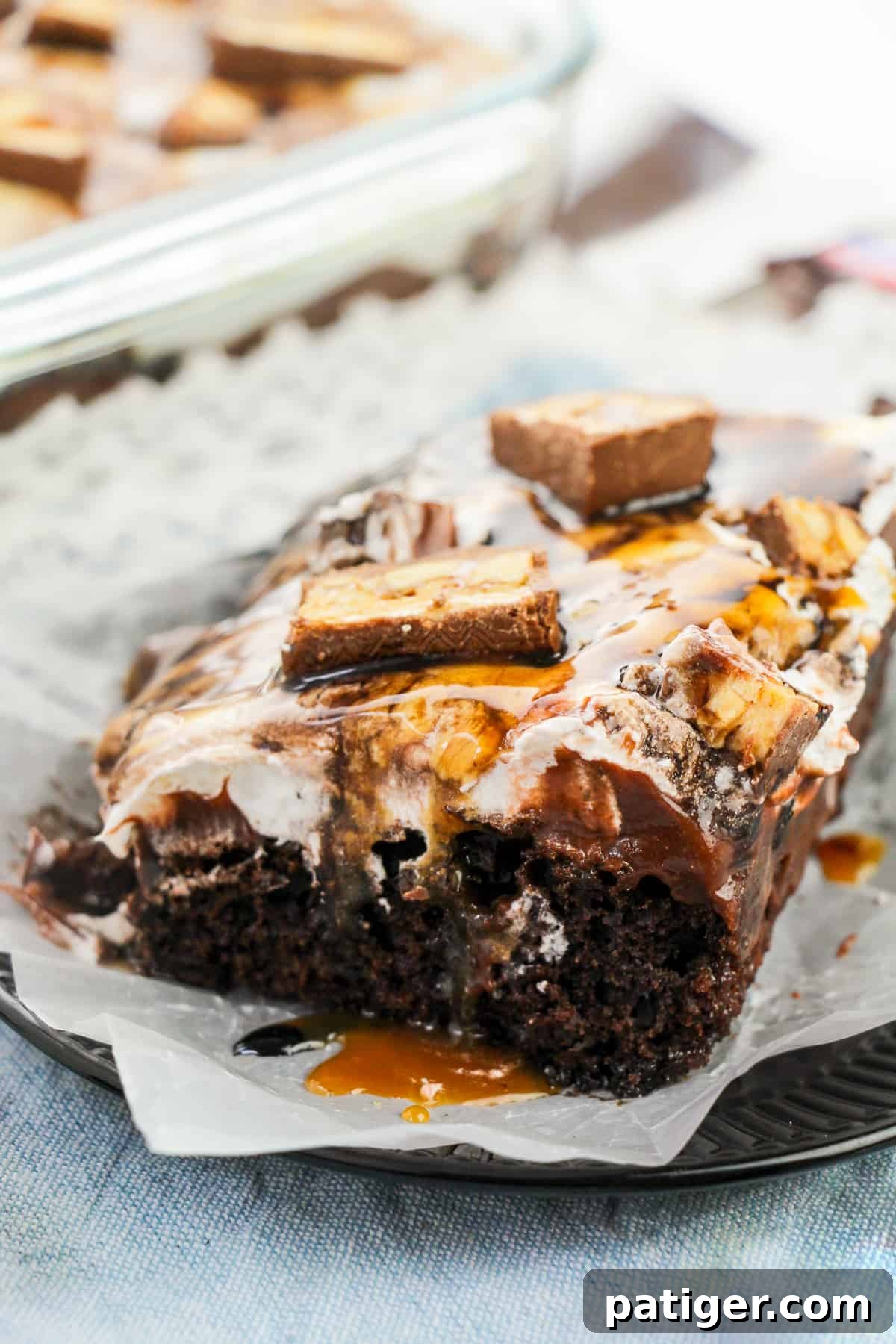 Chocolate snickers poke cake dripping with chocolate and caramel sauces, highlighting its rich and decadent nature.