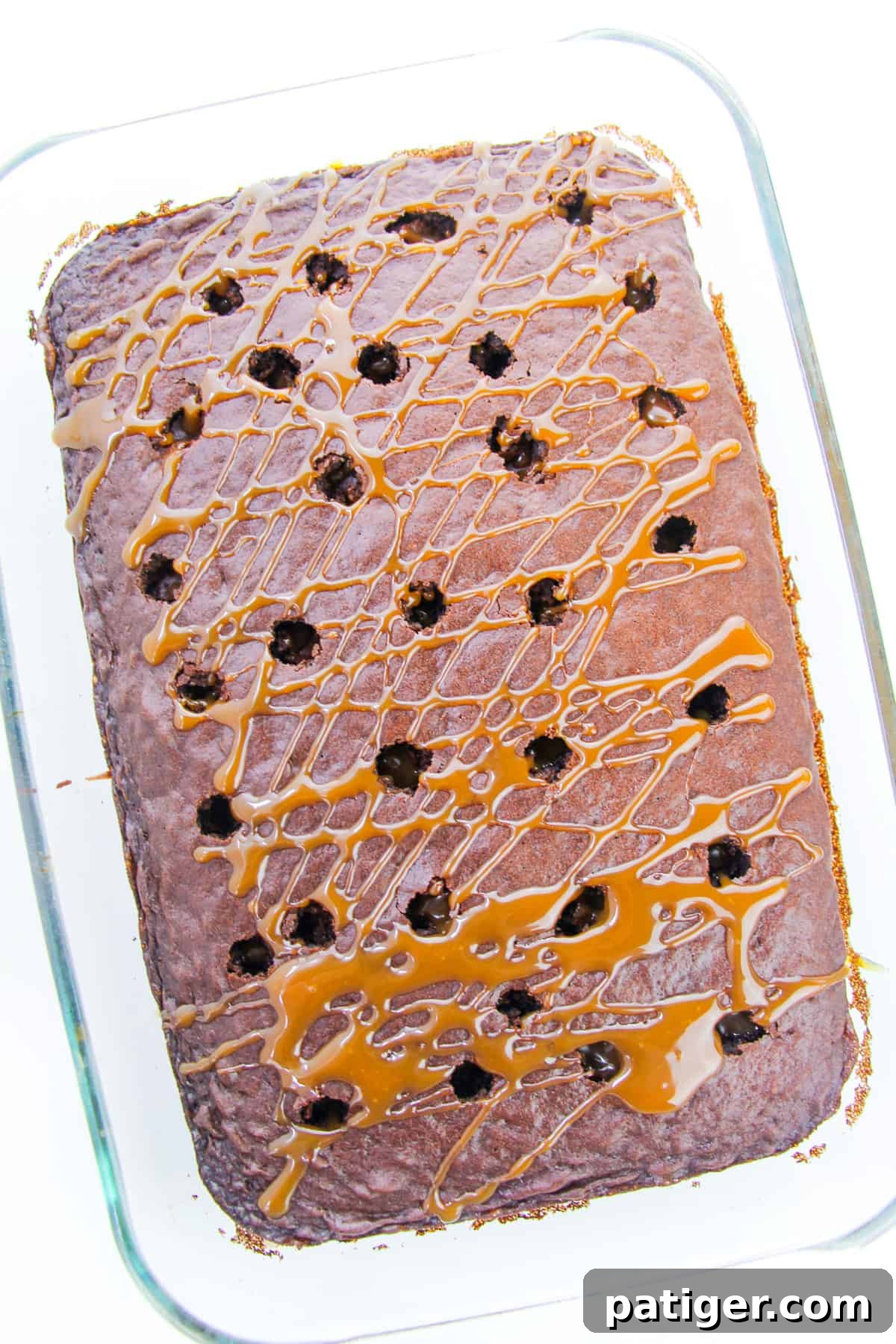 Chocolate Poke Cake with Caramel Sauce drizzled over the top, sinking into the poked holes.