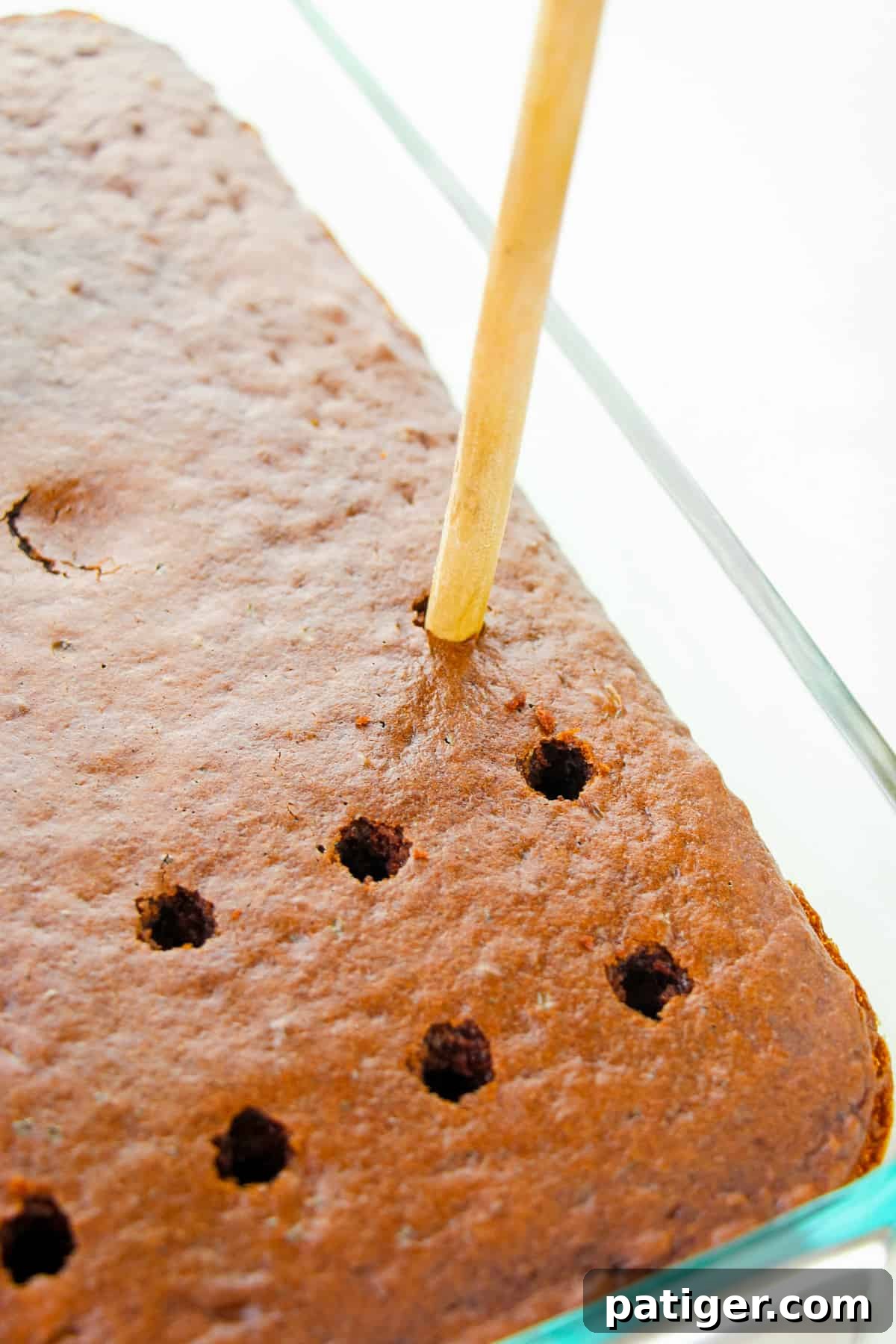 Cookies & Cream Poke Perfection 6 handle of wooden spoon poking holes 1 inch apart in chocolate cake