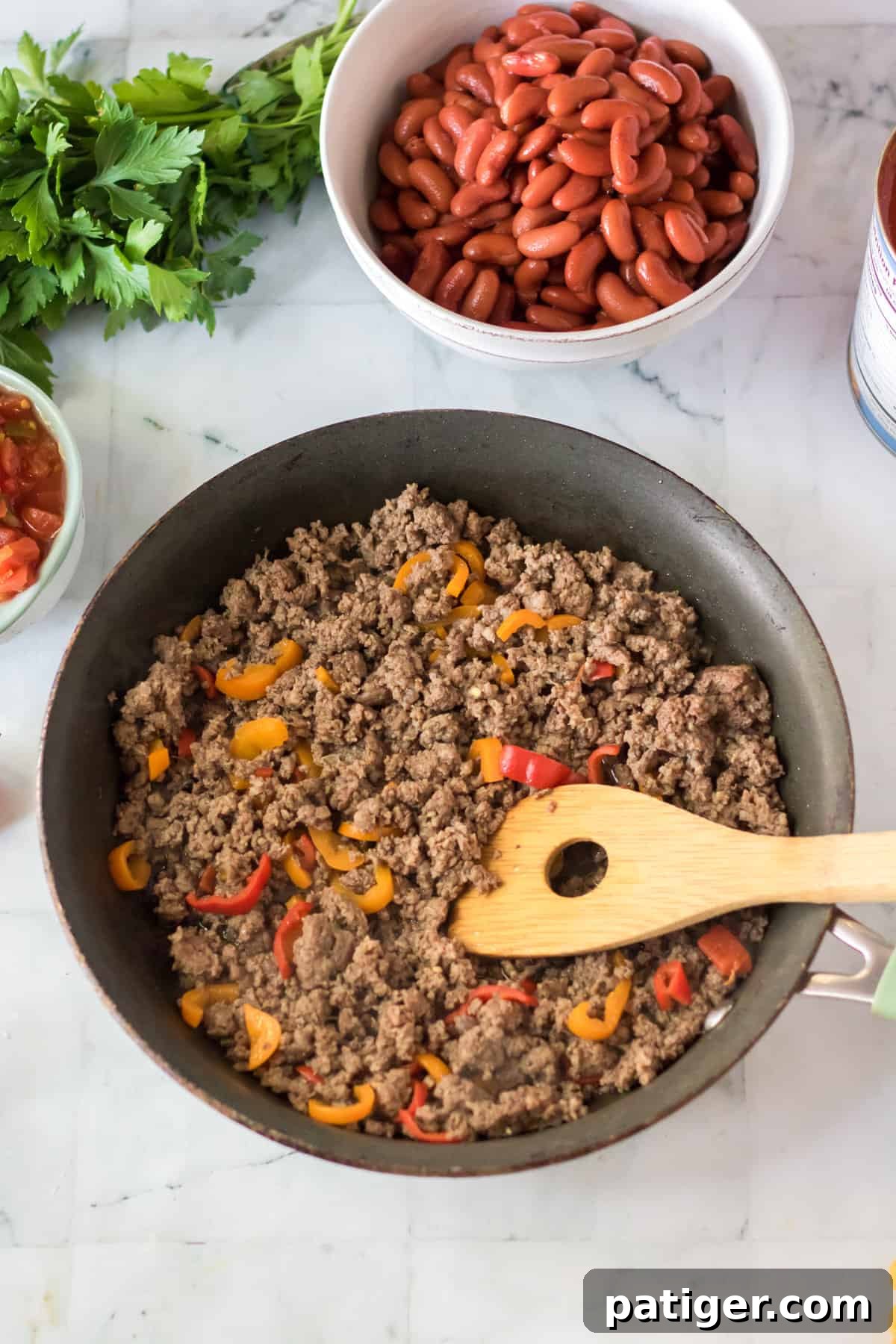 Browned ground beef and bell peppers cooking in a skillet.