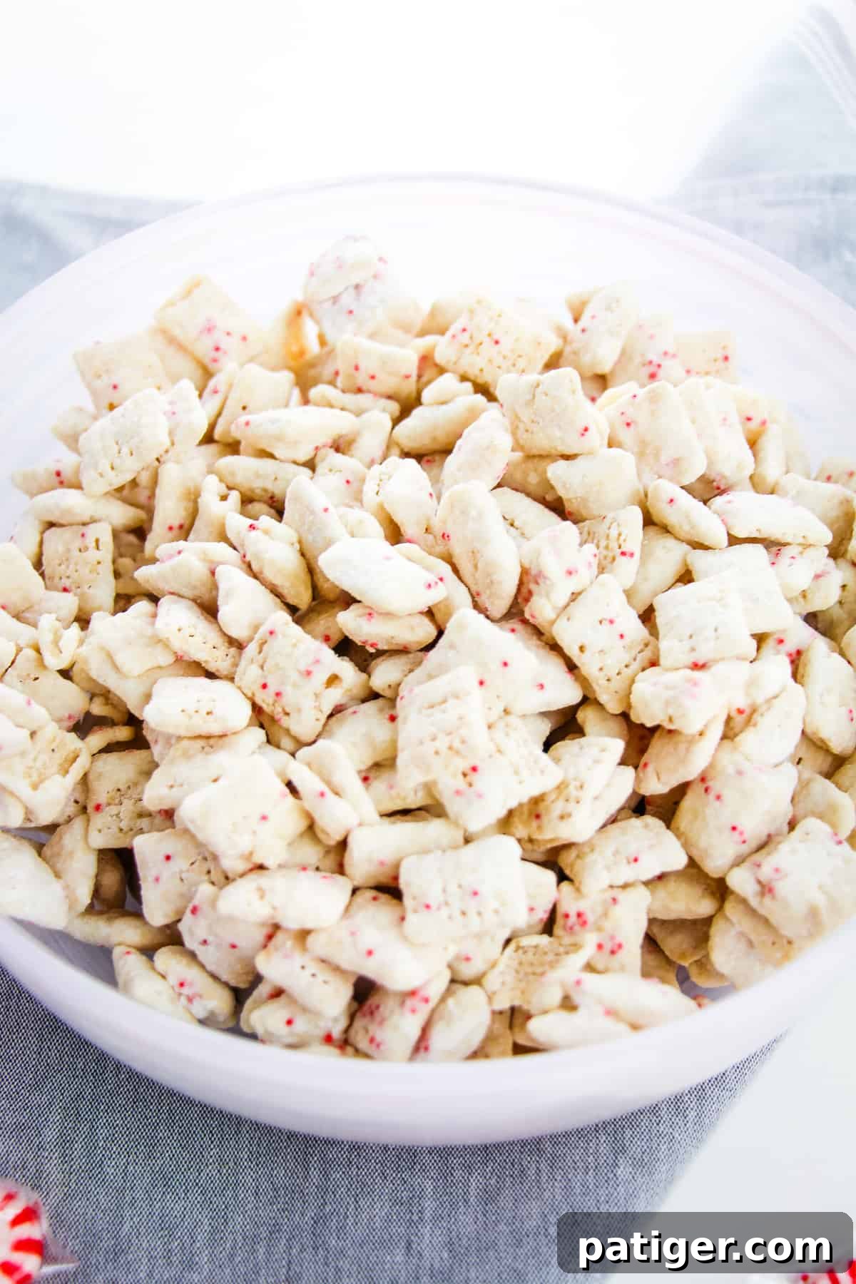 Winter Mint Bark Buddy Bites 3 A large serving bowl overflowing with delicious Peppermint Bark Muddy Buddies, showcasing the festive colors and texture.