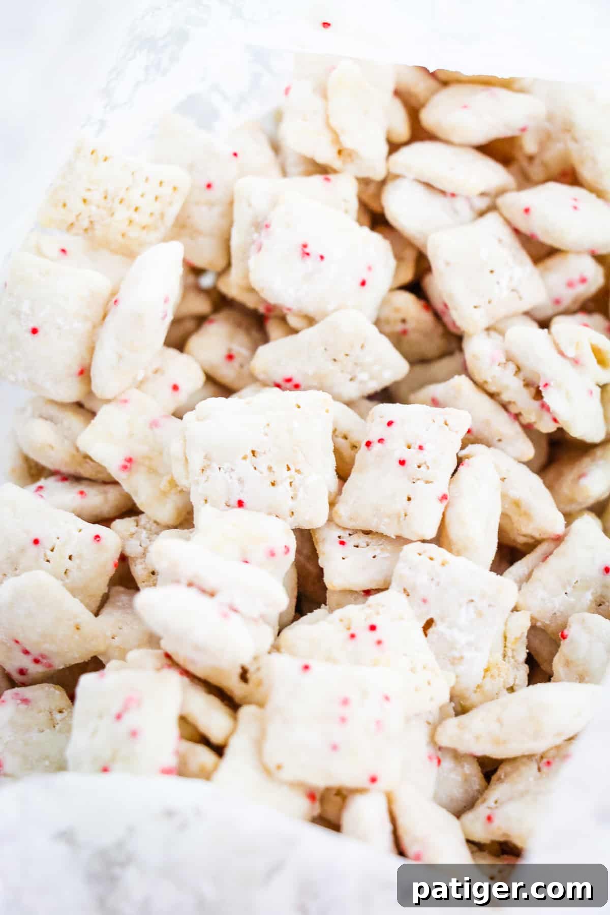 Winter Mint Bark Buddy Bites 9 Peppermint Bark Muddy Buddies inside a plastic zip-top baggie, being shaken to coat with powdered sugar.