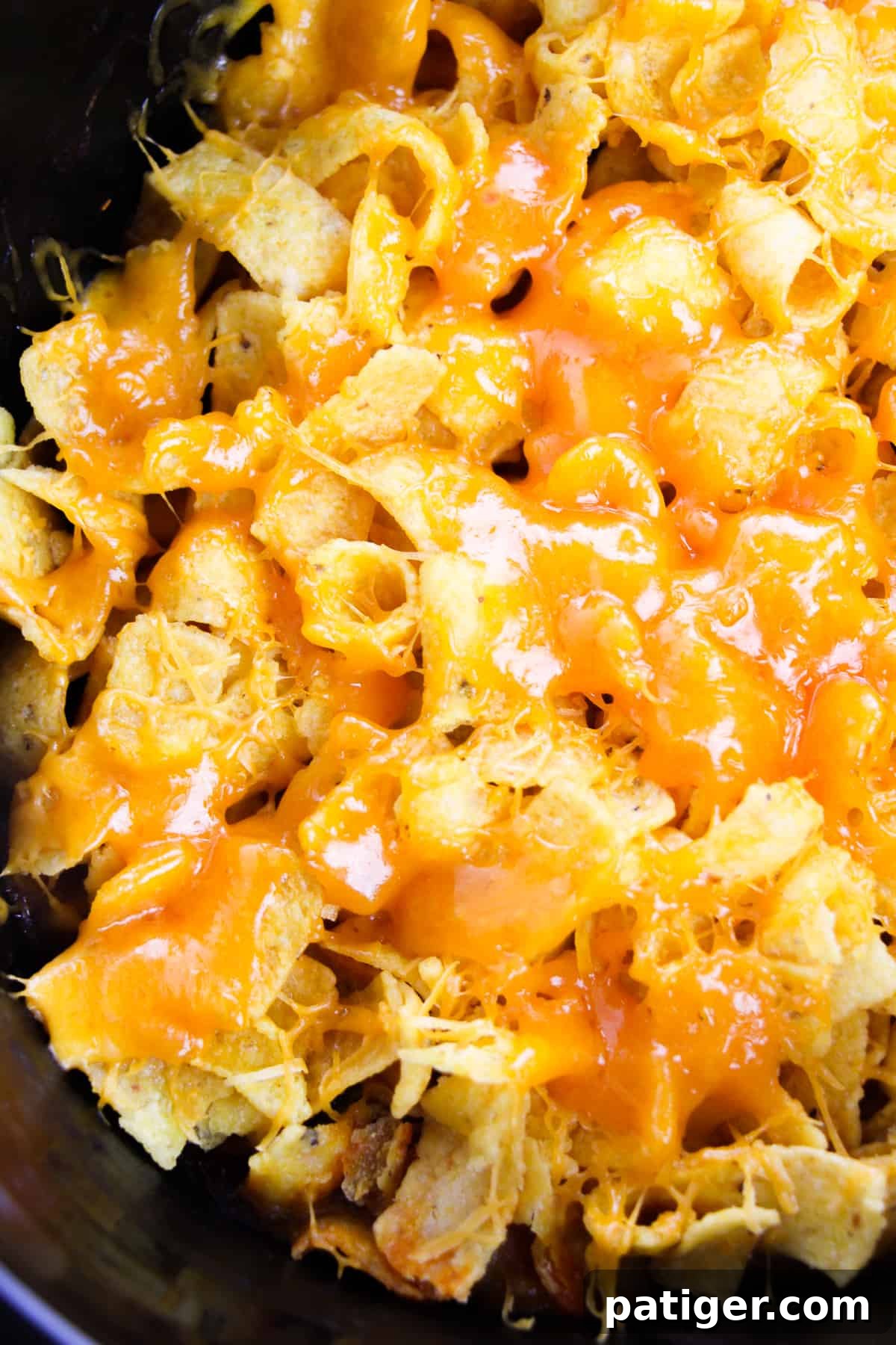 Slow Cooker Cheesy Frito Chili Bake 4 Crockpot filled with Frito Pie, generously topped with a melted layer of cheddar cheese