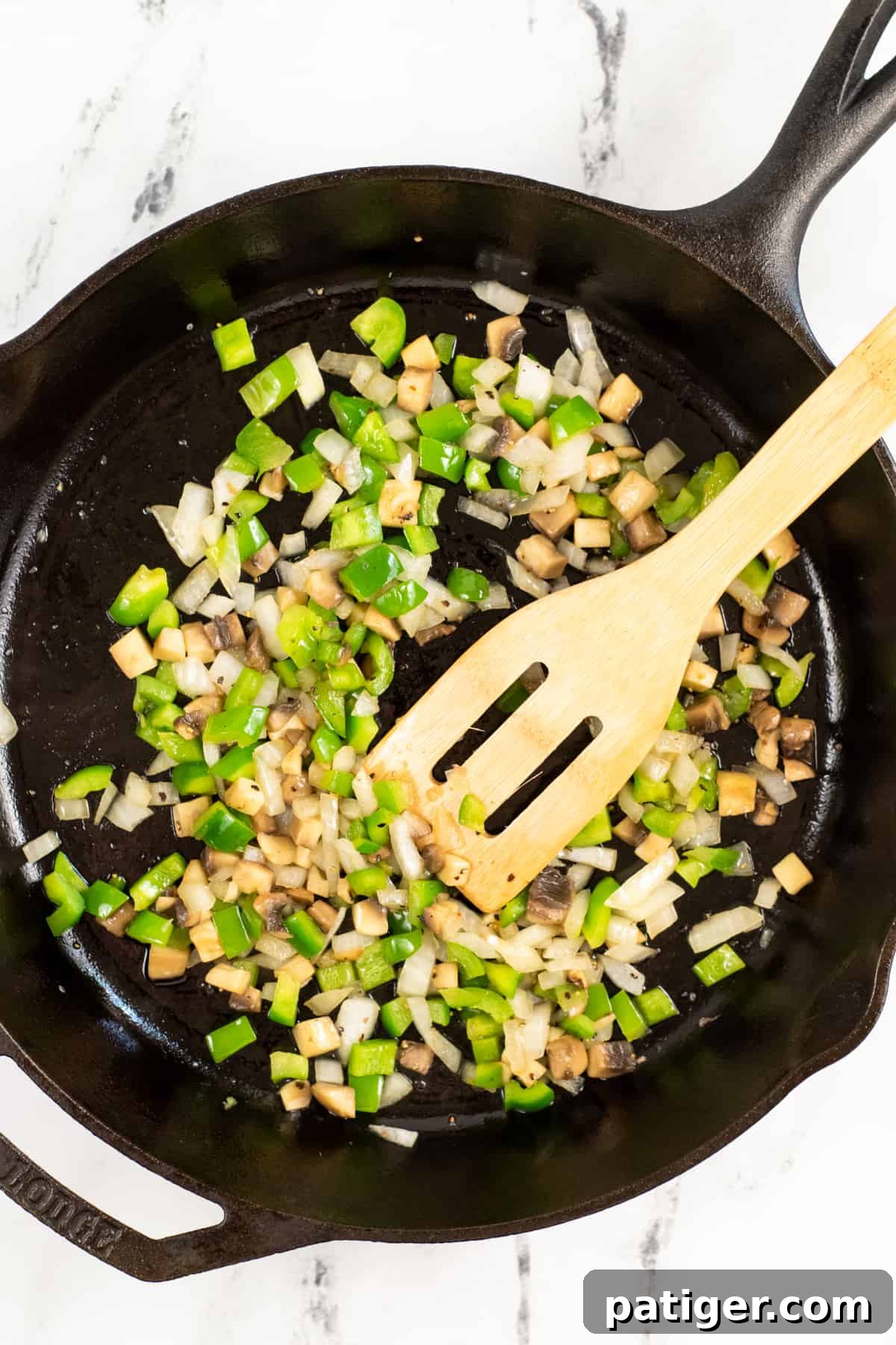 Chopped green peppers, onion, and mushrooms sizzling in a skillet