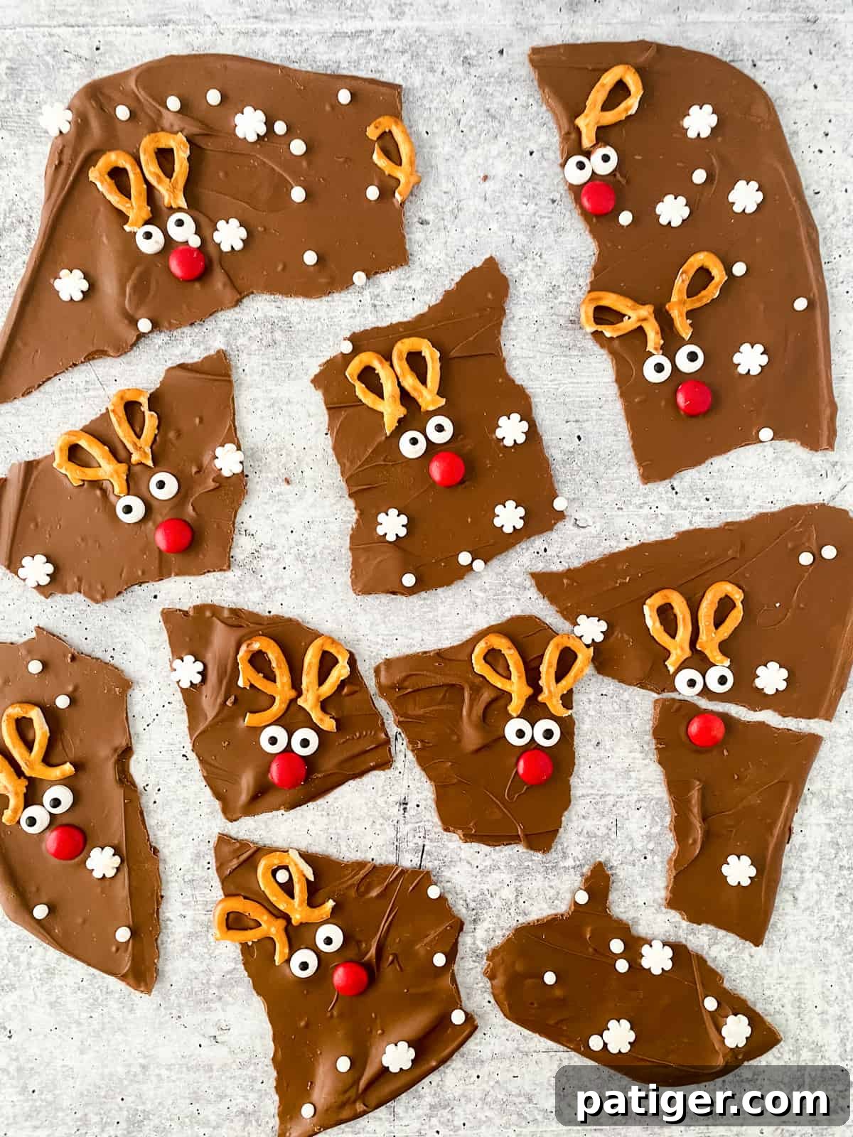 Chocolate reindeer bark broken into irregularly shaped pieces, each decorated with broken pretzels, candy eyes, and a red M&M to look like Rudolph the red-nosed reindeer