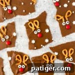 Chocolate reindeer bark broken into irregularly shaped pieces, each decorated with broken pretzels, candy eyes, and a red M&M to look like Rudolph the red-nosed reindeer
