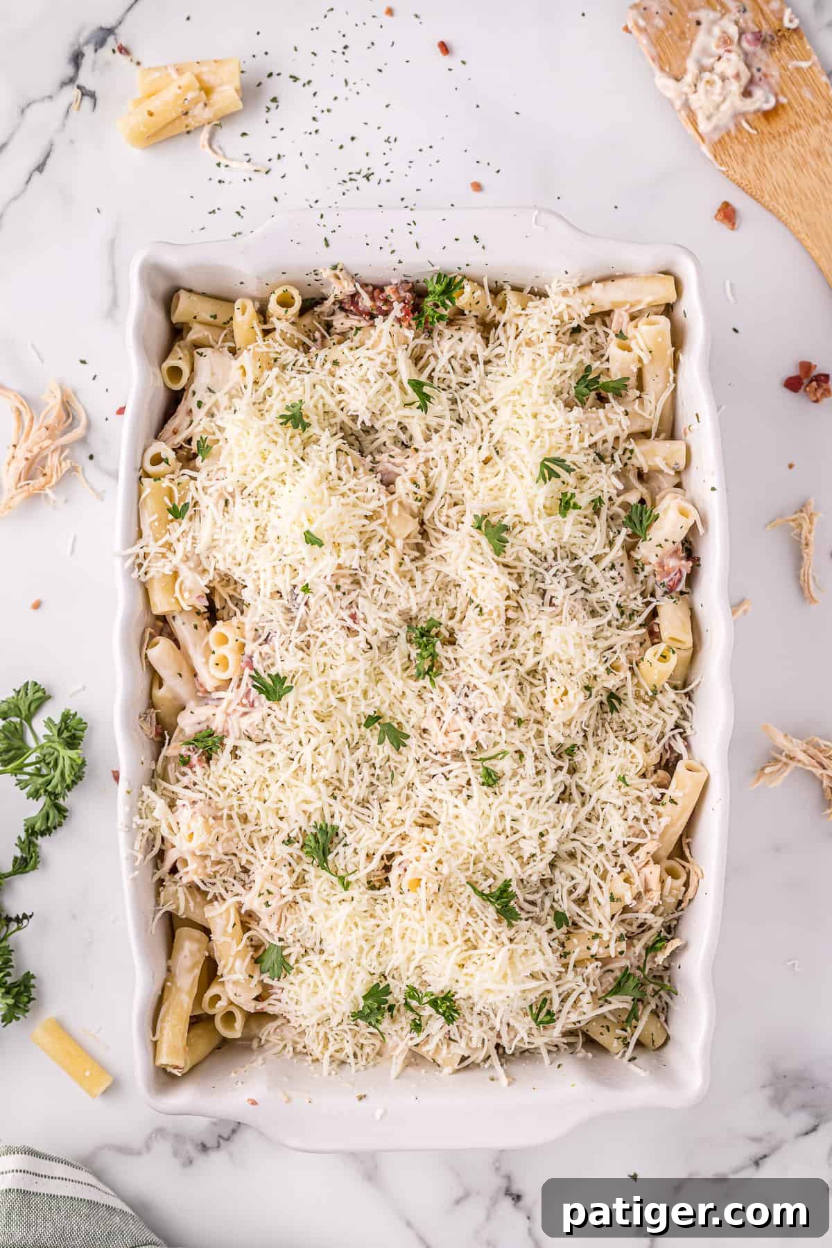 Golden Alfredo Chicken Bake 9 Unbaked chicken Alfredo casserole, beautifully topped with shredded cheese and fresh parsley, ready for the oven.