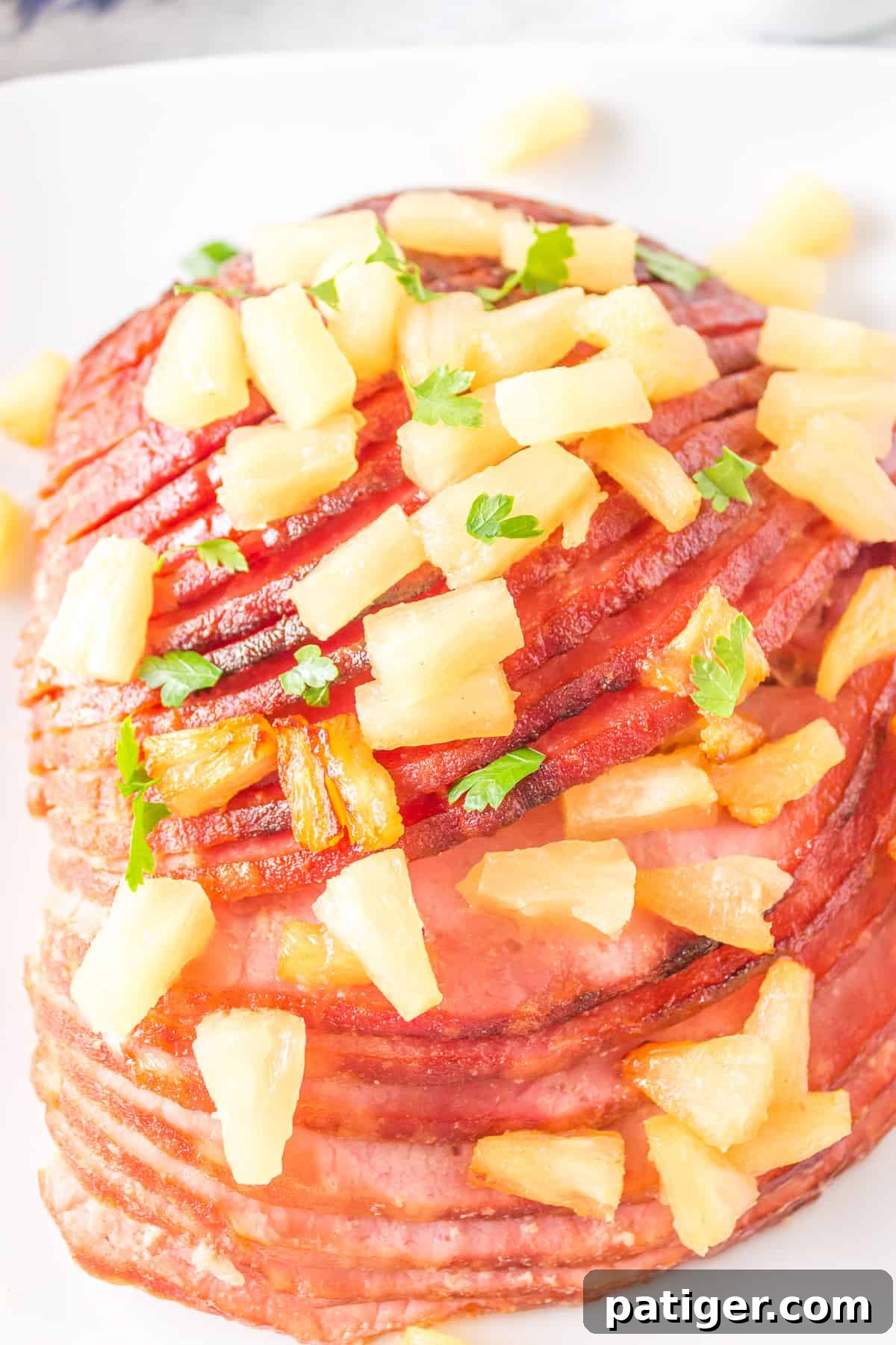 Golden brown air fryer spiral glazed ham with bright pineapple chunks on top, presented on an elegant white platter, ready to serve.