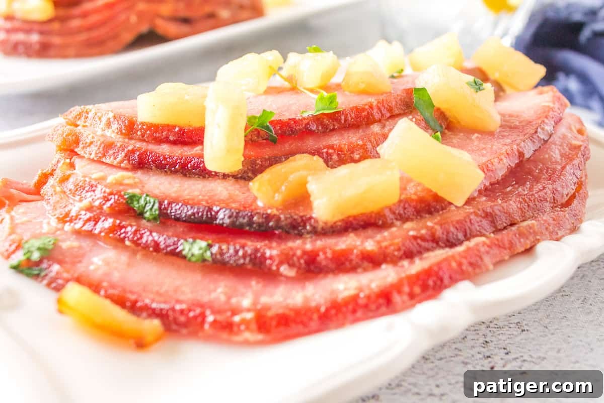 Beautifully sliced air-fried ham garnished with pineapple and a rich maple glaze, artfully arranged for a holiday meal.
