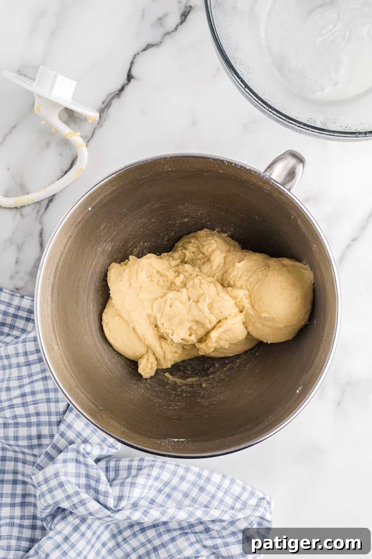 Mashed potato roll dough in ball in bowl of stand mixer. Dough hook attachment is net to the bowl