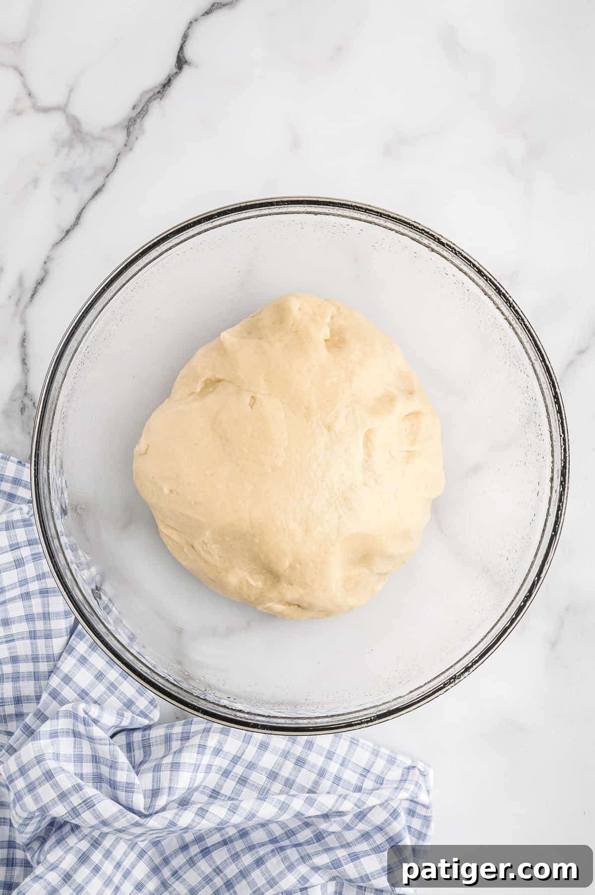Potato roll dough rising in glass bowl