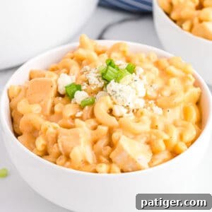 Buffalo Chicken Mac and Cheese in white bowl topped with blue cheese and scallions.