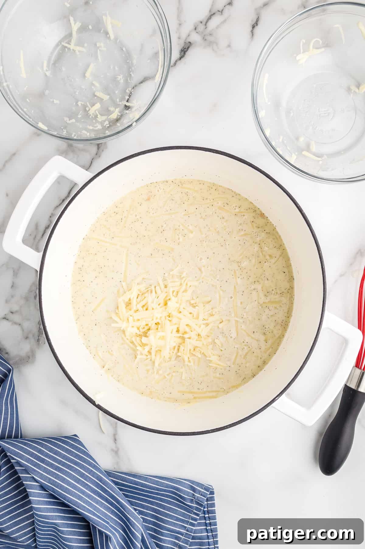 Buffalo Bliss Mac & Cheese 9 Shredded cheddar and Monterey Jack cheeses melting into the white sauce in a large pot, creating a rich, creamy cheese sauce.