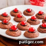 A small image of chocolate cherry thumbprint cookies on a white plate, encouraging engagement.