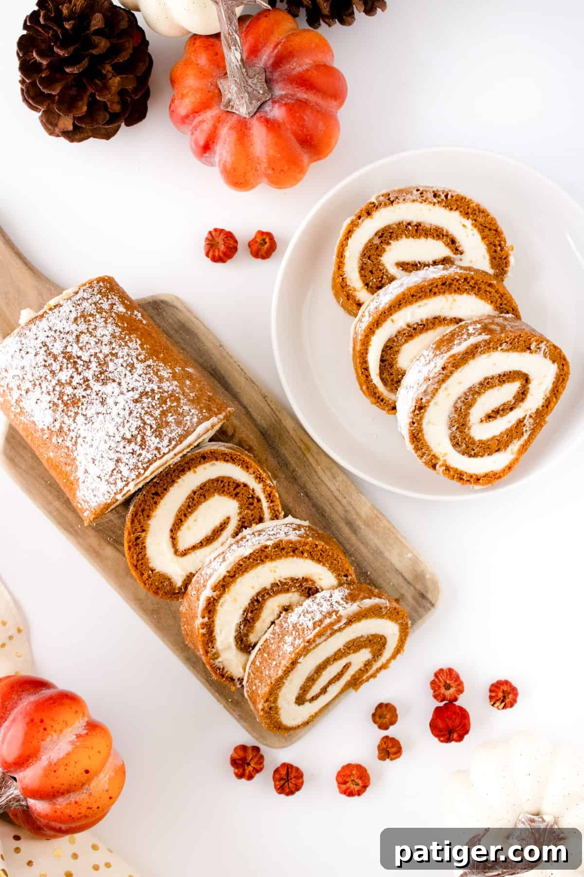 Spiced Pumpkin Swirl Cake 3 Slices of Pumpkin Roll Cake on a white plate and a wooden cutting board, with decorative small pumpkins nearby.