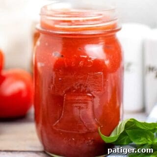 Homemade pizza sauce in mason jar on wooden table, ready to be used for pizza.