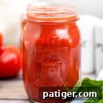 Homemade pizza sauce in mason jar on wooden table, close up view.