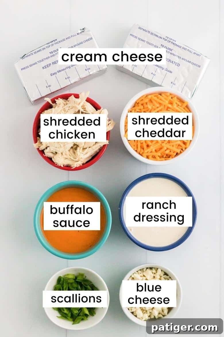 Game Day Crockpot Buffalo Chicken Dip 5 Two blocks of cream cheese, shredded cooked chicken, a bowl of shredded cheddar cheese, buffalo sauce, ranch dressing, fresh scallions, and crumbled blue cheese, all laid out for crockpot buffalo chicken dip.