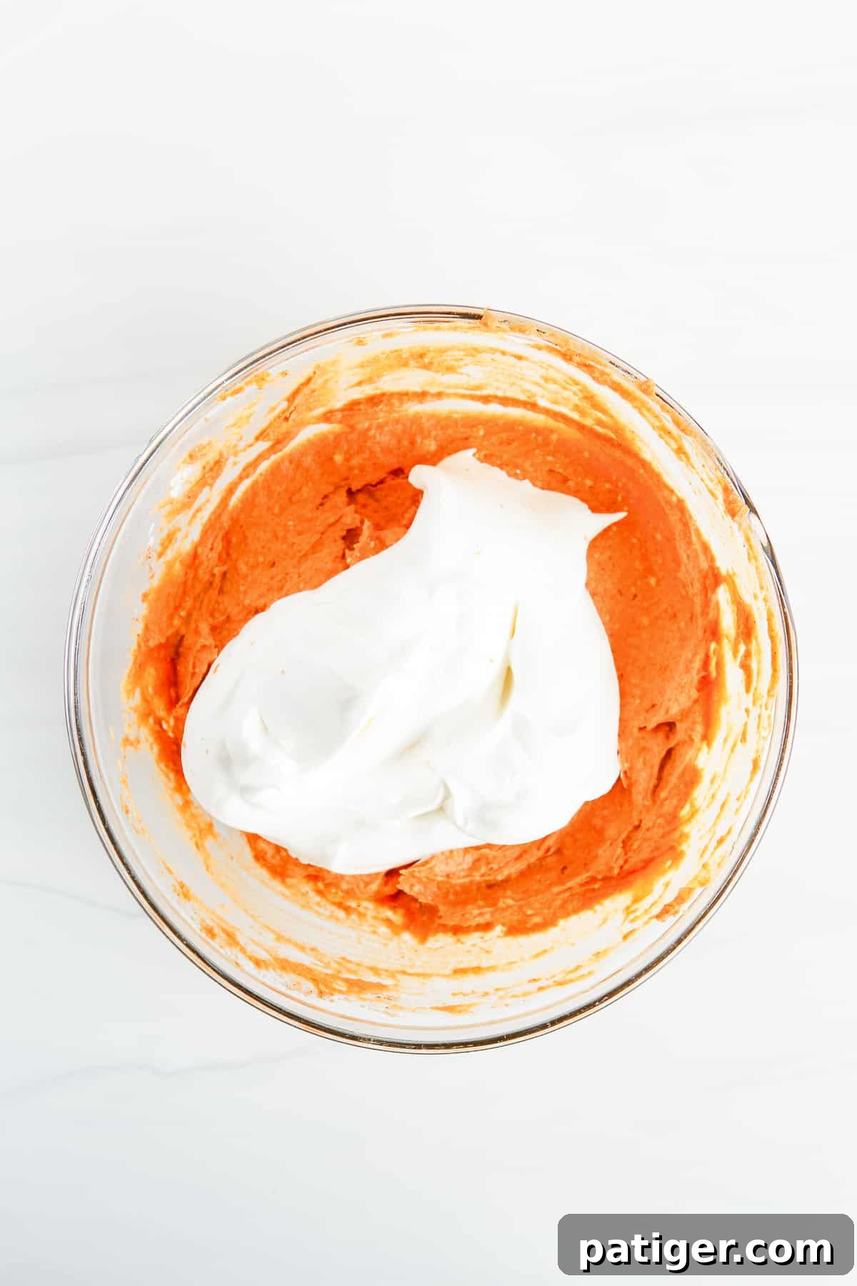 Pillowy Pumpkin Delight 7 An in-process image showing fluffy Cool Whip being gently folded into the smooth pumpkin dip base within a mixing bowl, creating the signature airy texture.