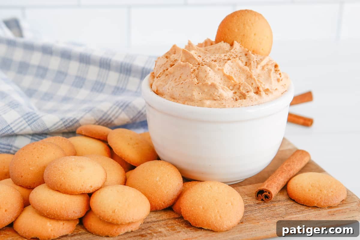 Pillowy Pumpkin Delight 8 A beautifully presented bowl of pumpkin fluff dip, perfectly chilled and ready to serve, surrounded by crisp vanilla cookies for dipping, inviting guests to indulge in this delightful autumn dessert.