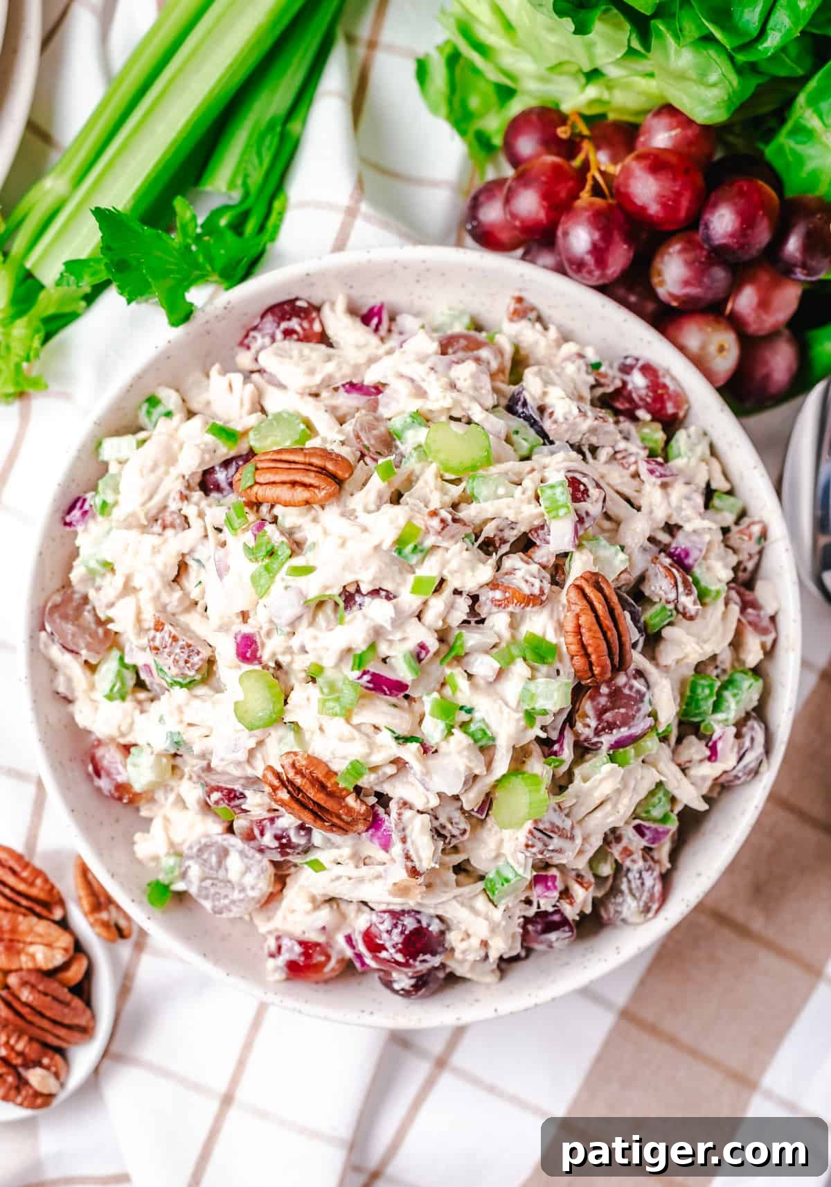 Signature Grape and Pecan Chicken Salad 6 A large, pristine white bowl generously filled with homemade chicken salad, richly mixed with vibrant red grapes, crunchy pecans, and crisp celery. This inviting image highlights the fresh ingredients and the luscious, creamy texture of the salad, ready for serving.