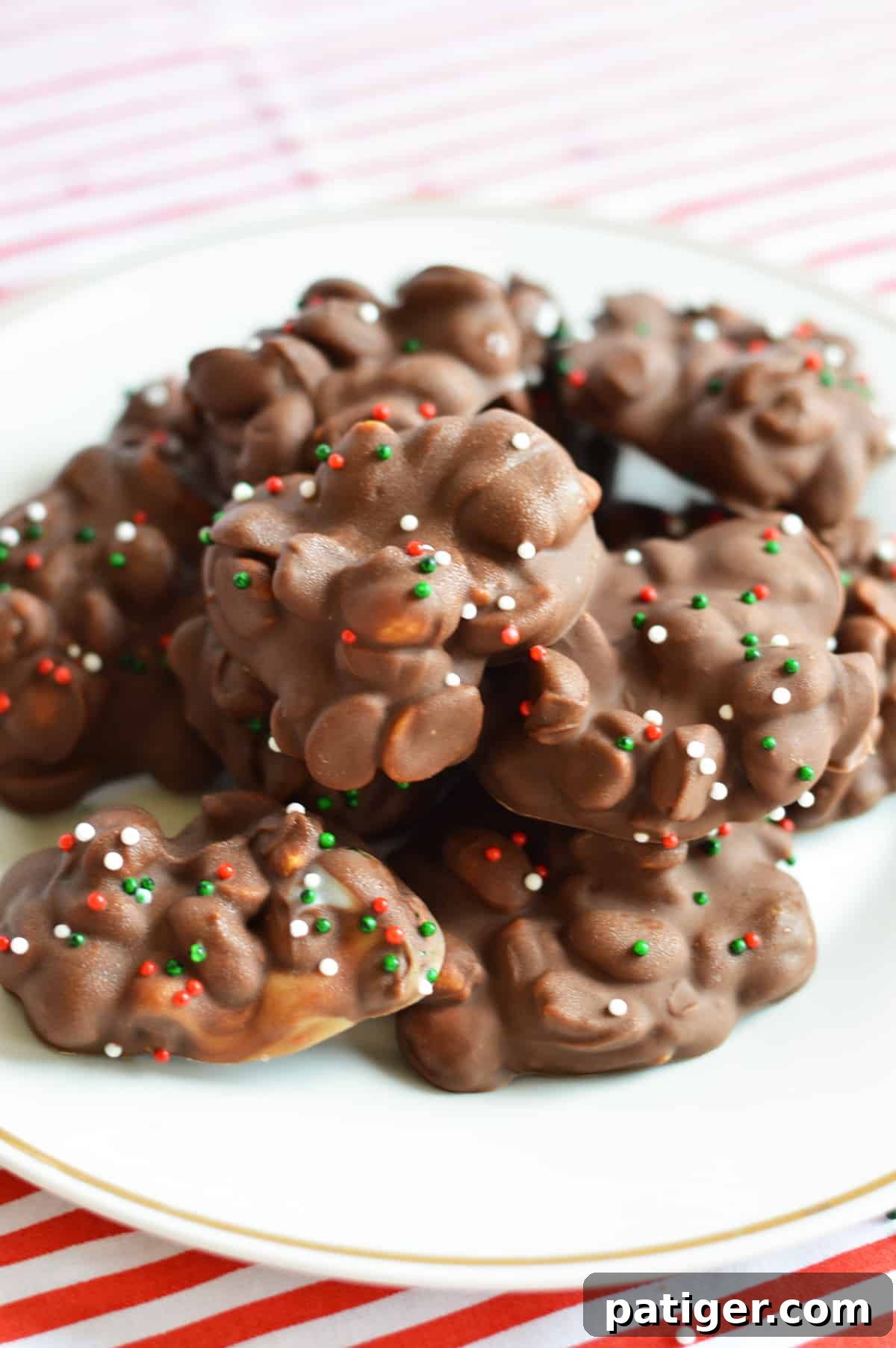 Crockpot candy with peanuts and christmas sprinkles on white plate
