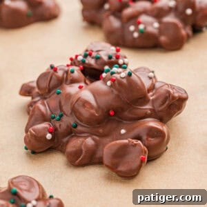 Crock pot candy (aka chocolate peanut clusters) with Christmas sprinkles on parchment paper.
