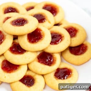Thumbprint cookies with jam centers piled on a white plate