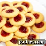 Thumbprint cookies with jam centers piled on a white plate
