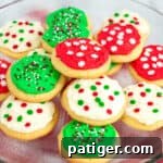 Platter of round frosted sugar cookies decorated with red, green, and white frosting and christmas sprinkles