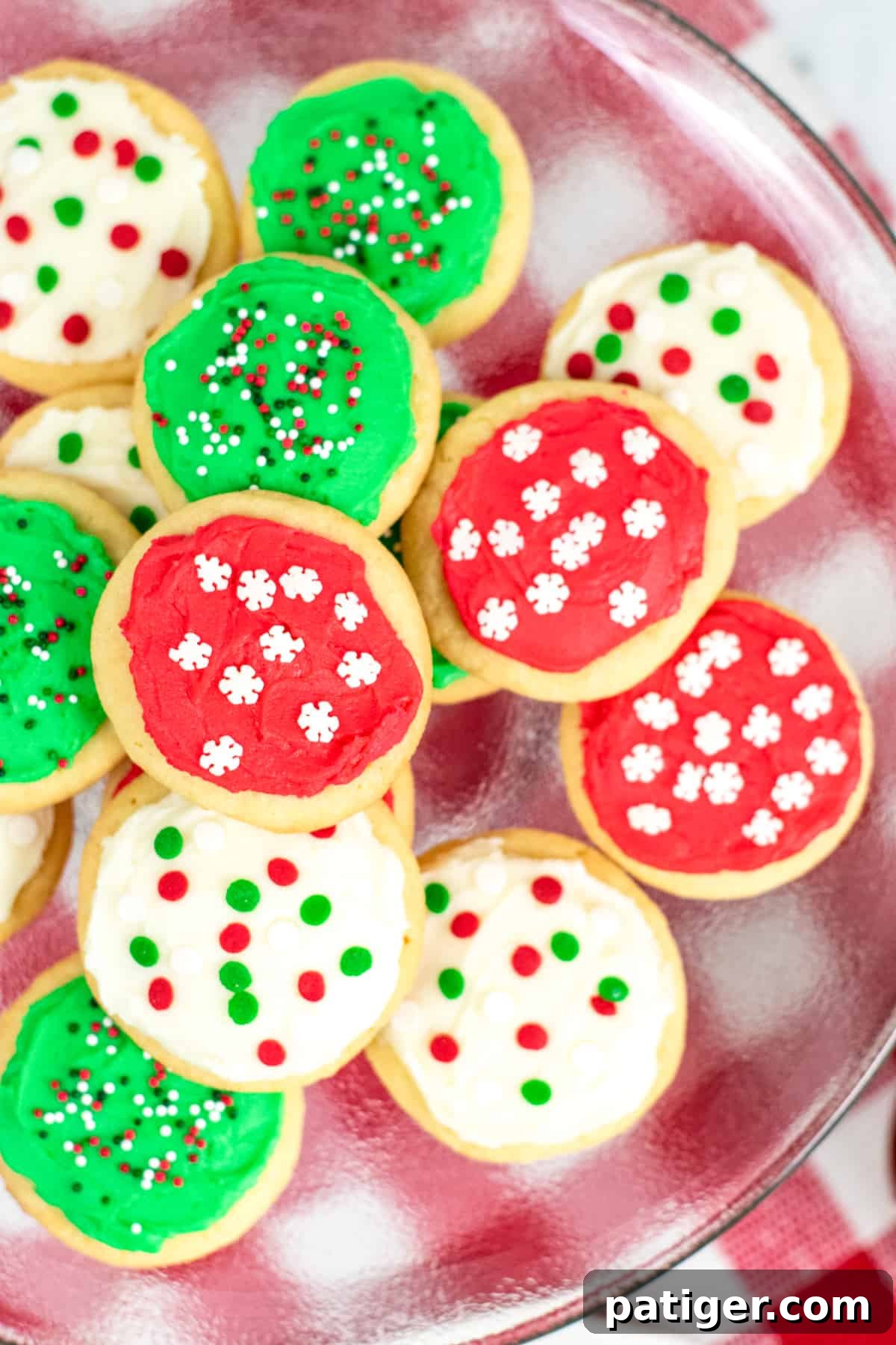Platter of round cookies topped with either red frosting, green frosting, or white frosting and red, white, and green sprinkles, ready for serving.
