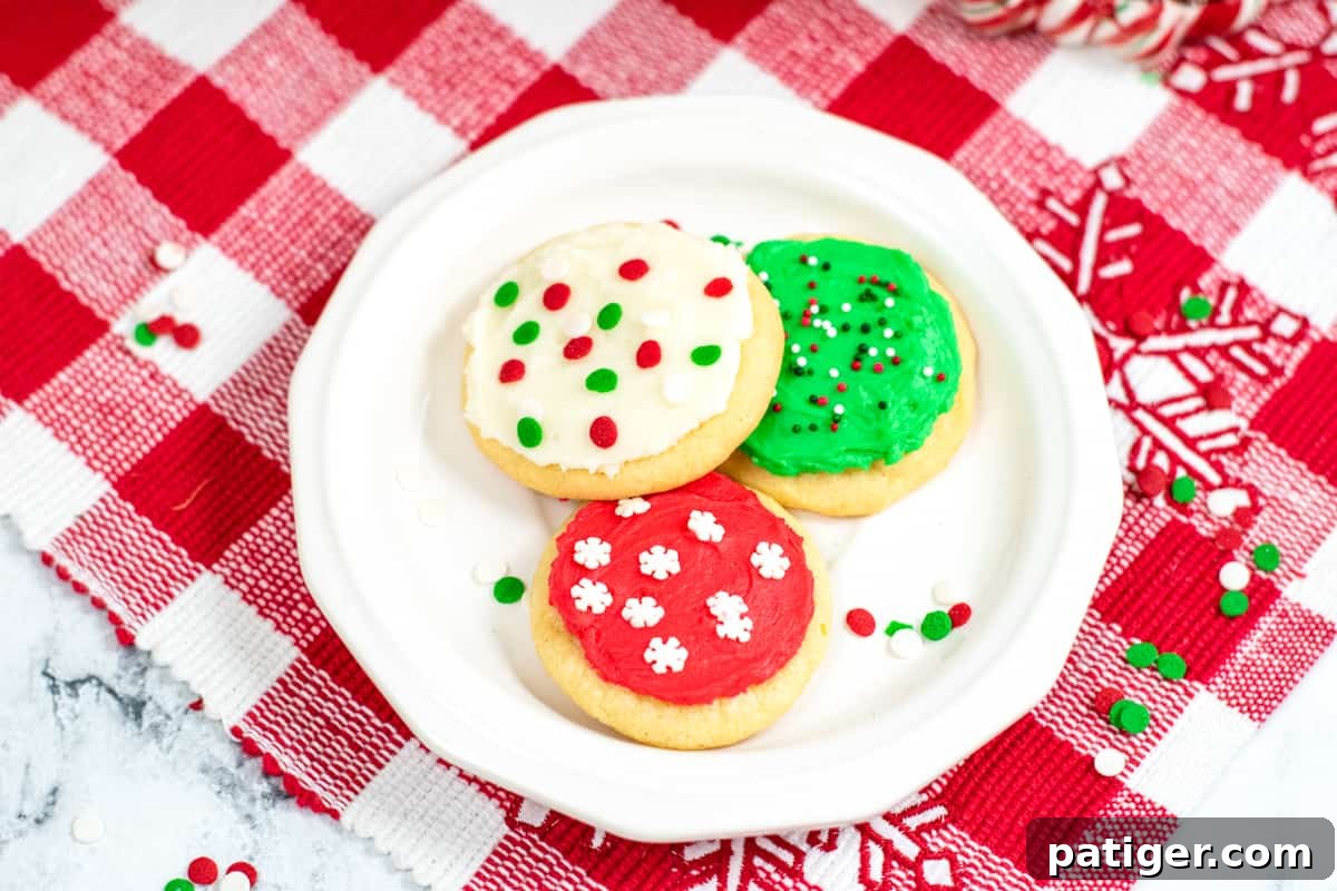 white dessert place with three frosted Christmas cookies, one red with white sprinkles; one green with green, white and red sprinkles; and one white with green and red confetti sprinkles, ready to be enjoyed.